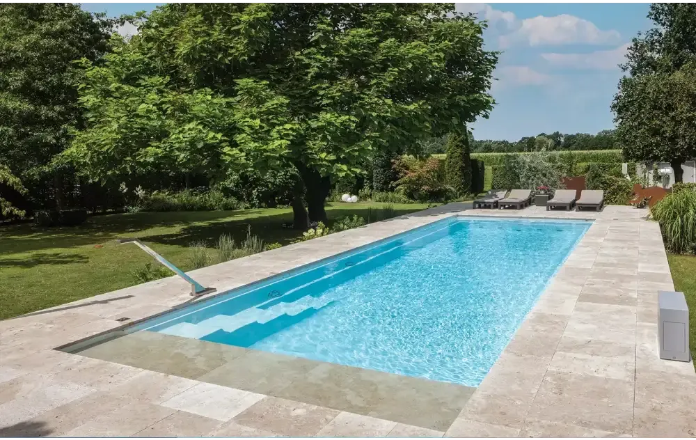 Leisurepools Definitive Hög vattenlinje rektangulär pool med klarblått vatten och beige stenplattor